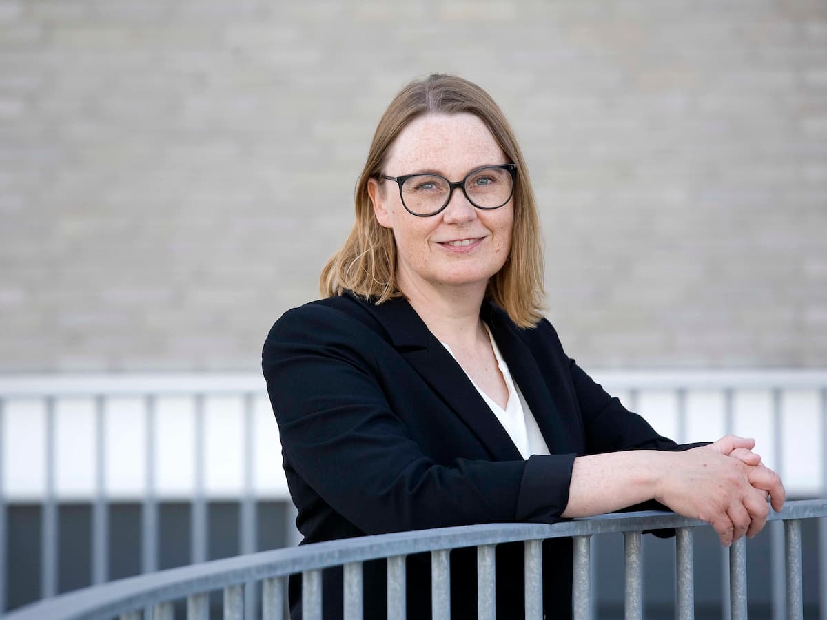 placeholder-image Lene Stampe, der hjælper med konflikthåndtering i organisationer, står med underarmene hvilende på et rækværk.
