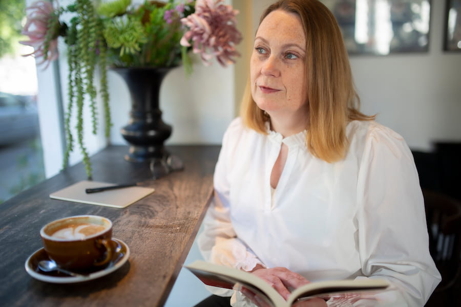Lene Stampe sidder med sin notesbog i en ledersparring på med en kop kaffe