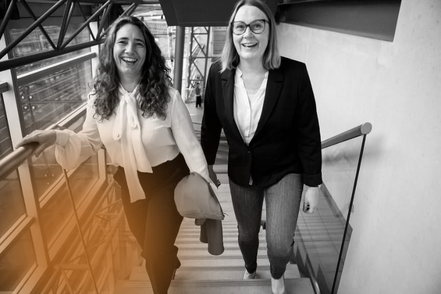 Lene Stampe og Randi Rich går smilende op ad en trappe klar til ledelsesudvikling